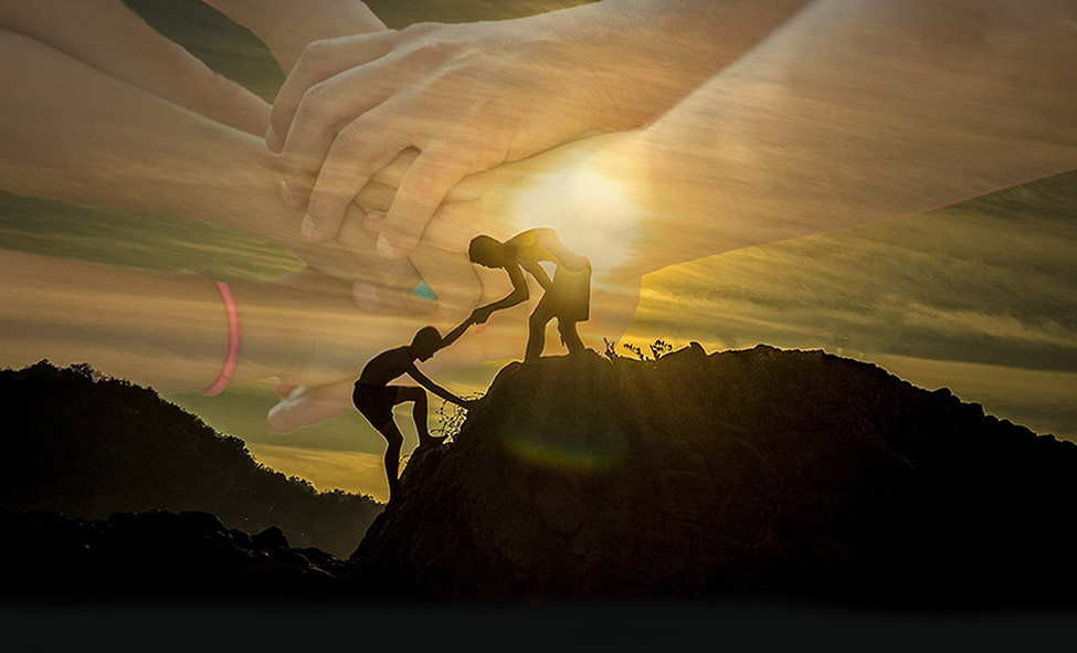 Person hilft anderer Person einen Berg hoch